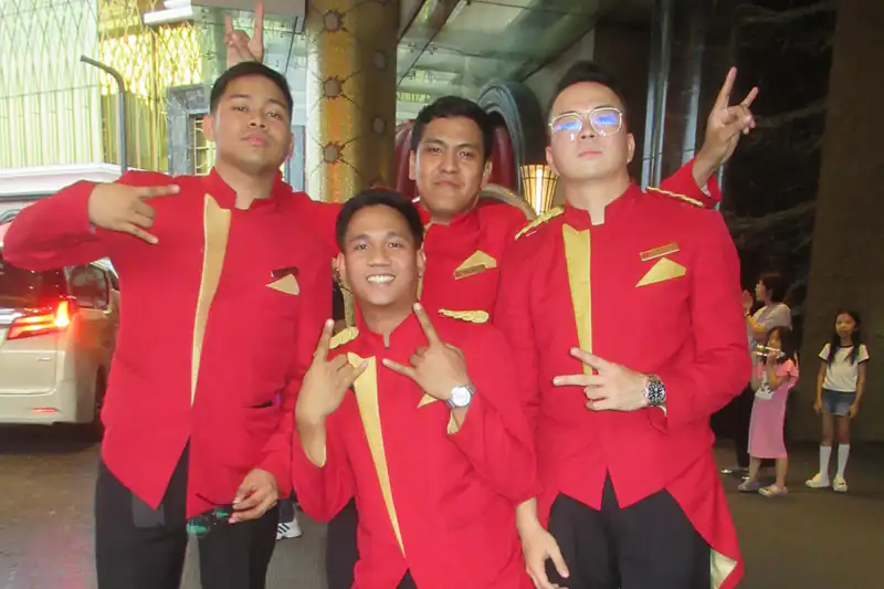 Uniformed resort staff posing at the entrance of an integrated resort in Manila