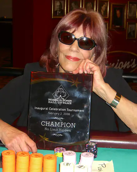Poker champion holding a trophy behind stacks of chips