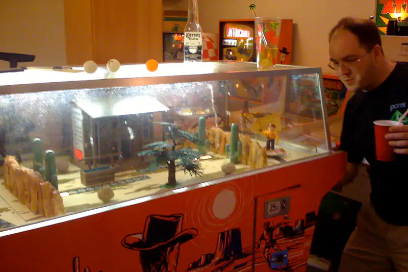 Man playing a coin-operated arcade shooting gallery
